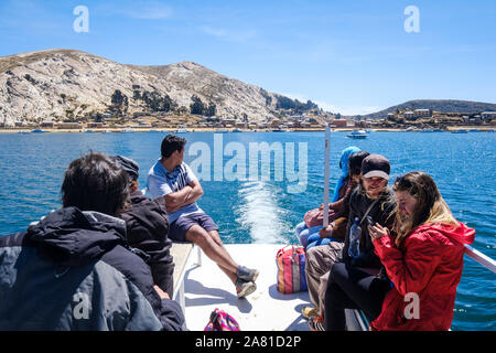 I turisti seduti sul ponte superiore di una barca di lasciare il porto della Comunità Challa lato dell'isola del sole nel Lago Titicaca, Bolivia Foto Stock