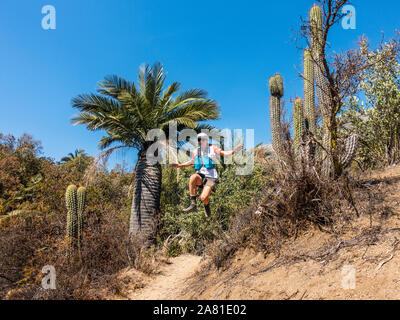 Giovane donna trail runner correre e saltare giù per un sentiero nel Parco Nazionale di La Campana nel centro del Cile. Foto Stock