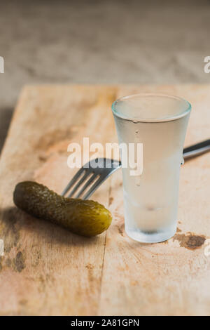 Cetriolo salato su una forchetta e un bicchiere di vodka sulla scheda - Russo ubriachezza Foto Stock