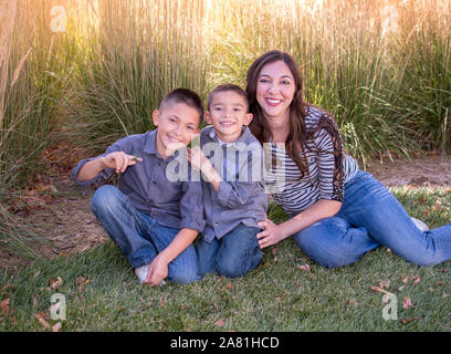 Una giovane famiglia composta da mamma e i suoi due figli, coccola contro un sfondo dorato, su di una bella giornata di caduta Foto Stock