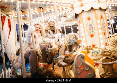 Foto di due donne equitazione sulla giostra nel parco di sera d'inverno Foto Stock