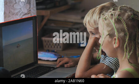 I bambini sono a sfogliare le foto su un computer portatile. Foto Stock