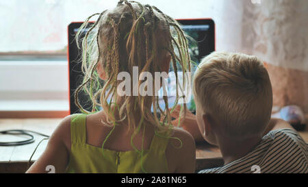 I bambini sono a sfogliare le foto su un computer portatile. Foto Stock