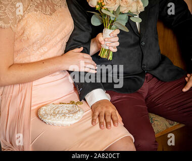 Close up della sposa e lo sposo in abbigliamento vintage seduto e toccando con la sposa bouquet di contenimento in attesa di sposarsi Foto Stock