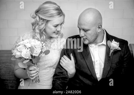 Nero e Whirte immagine di perdere fino della sposa e lo sposo in abbigliamento vintage seduto e toccando con la sposa bouquet di contenimento in attesa di sposarsi Foto Stock