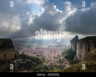 Sunray brilla attraverso la moody nuvole sulla città Kalabaky accoccolato tra le scogliere di montagna Foto Stock