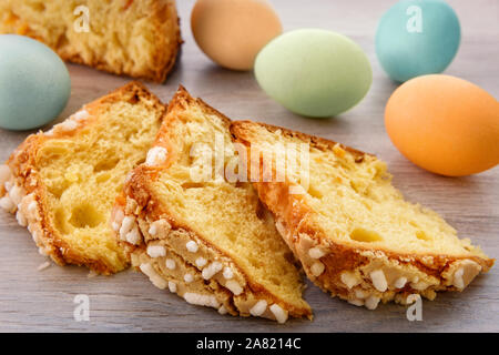 Fette di torta di Pasqua e uova colorate sono su un tavolo di legno alto. Foto Stock