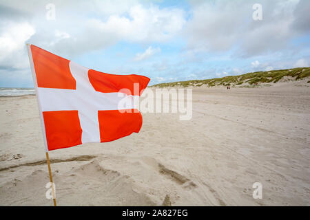 Bandiera danese nel vento in spiaggia di sabbia vicino a Blavand, Jutland in Danimarca Foto Stock