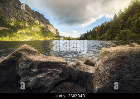 Lago di montagna con rocce in primo piano. Poprad Tarn, Alti Tatra, Slovacchia. Foto Stock