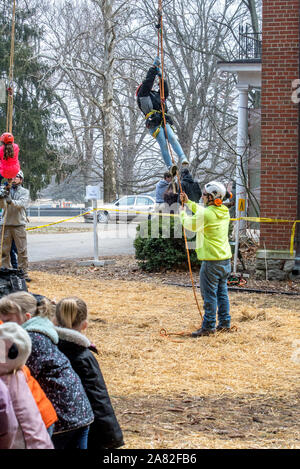 Marzo 17, 2019 Indiana America; i bambini sono sollevati in aria mediante una struttura ad albero dei lavoratori mentre una linea di bambini attendere il loro turno, in corrispondenza di un albero di dimostrazione nel piegare Foto Stock
