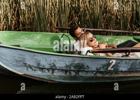 Coppia giovane rilassante gita in barca sul fiume vicino a canneto di sedge Foto Stock