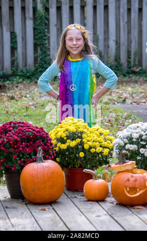 Un simpatico bambina pone in un colorato costume hippie per un Halloween Trick or Treat Foto Stock