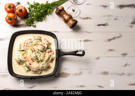 Colore fatti a mano ravioli pasta; multi-colore di ravioli di pasta a un nero padella di ferro, in legno bianco sullo sfondo della tabella. Foto Stock