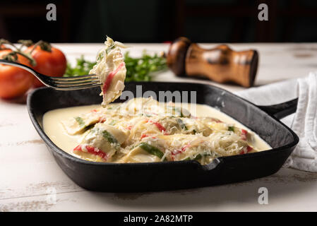 Colore fatti a mano ravioli pasta; multi-colore di ravioli di pasta a un nero padella di ferro, in legno bianco sullo sfondo della tabella. Foto Stock