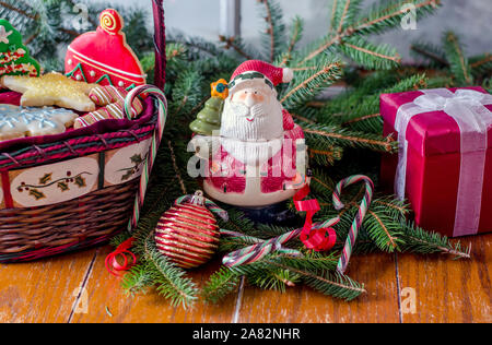 Un cestello di cookie e di santa statua con ornamenti. Una vacanza ancora vita Foto Stock