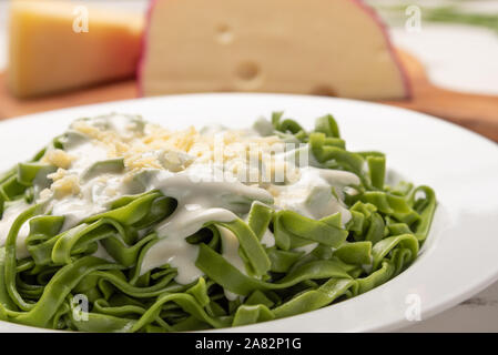 In casa di greeen spinaci fettuccine con salsa besciamella in una piastra bianca, tavola in legno rustico sfondo, luce morbida. Italian food style Foto Stock