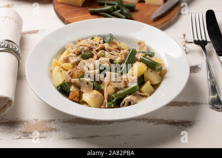 In casa i Pizzoccheri alla valtellinese; un tradizionale short tagliatelle tipico della provincia Italiana settentrionale della Valtellina. Piastra bianca su legno Foto Stock