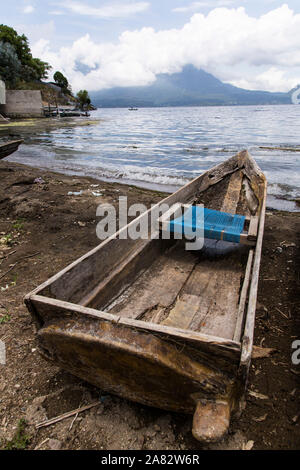 Un cayuco o barca da pesca sulla riva del lago Atitilan a San Antonio Palopó, Guatemala con una barca da pesca sul lago Atitlan e San Pedro Volcan Foto Stock