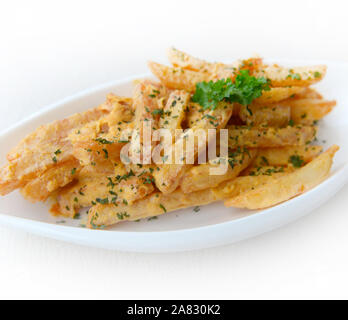 Le patatine fritte condite con uovo salato sulla piastra bianca su sfondo bianco. cucina fusion concetto.Il fuoco selettivo. Foto Stock