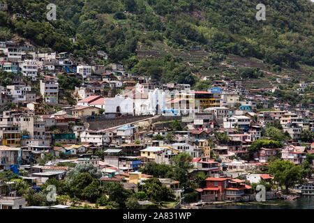 Vista in lontananza San Antonio Palopo, Guatemala, sulla riva del lago Atitlan. I ripidi pendii in discesa al lago, che è un extinict cratere vulcanico Foto Stock