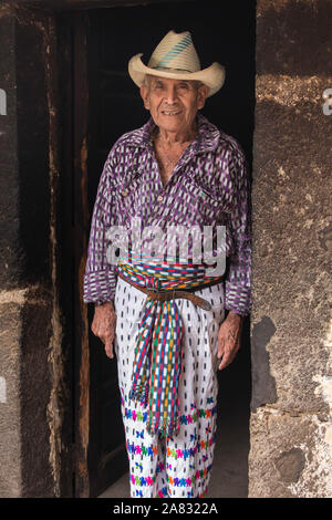 90 anni Maya Tzutujil uomo in abito tradizionale sta alla porta della sua casa di San Pedro La Laguna, Guatemala. Foto Stock