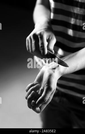 Foto in bianco e nero di donna vene di taglio con il coltello, primo piano. Concetto di suicidio Foto Stock