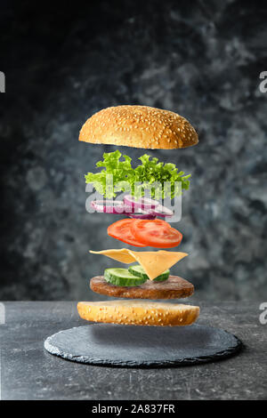 Gustosa burger con battenti ingredienti su sfondo scuro Foto Stock