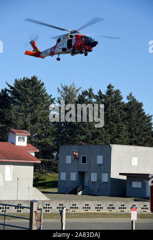 Petty Officer di terza classe Bryan Evans, una sopravvivenza di aviazione tecnico al Coast Guard Settore Columbia River, viene abbassata da un MH-60 Jayhawk elicottero per aprire la finestra di un edificio al Camp Rilea operazioni militari nel Terreno urbano villaggio in Warrenton, Ore., nov. 1, 2019. Questa ricerca e salvataggio in aree urbane evoluzione di formazione è stata condotta in collaborazione con i membri dell' aviazione Training Center Mobile. (U.S. Coast Guard foto di Sottufficiali di terza classe Trevor Lilburn) Foto Stock