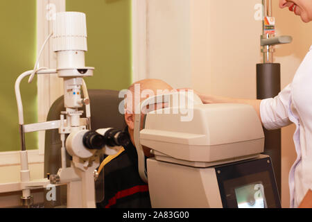 Un uomo più anziano tenendo un occhio test esame presso una clinica ottici Foto Stock