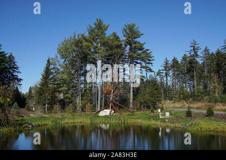 Boothbay, ME / STATI UNITI D'America - 19 Ottobre 2019: Stagno nella costa del Maine Giardini botanici decorata con un Steve Tobin radici in acciaio l'installazione Foto Stock