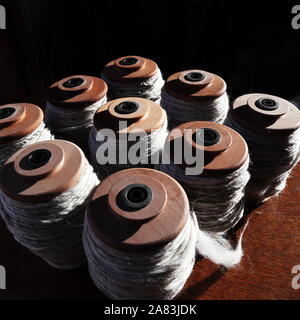 Nove ruota di filatura rocche riempito con handspun, grigio chiaro, il filo non colorato Foto Stock