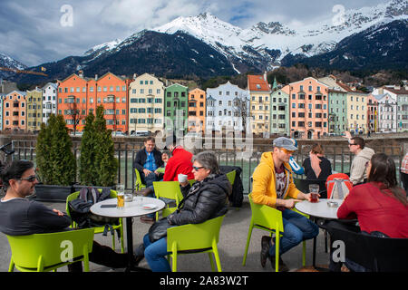 Ristorante e case colorate sul fiume Inn con neve montagne dietro, Innsbruck, in Tirolo, Austria Foto Stock