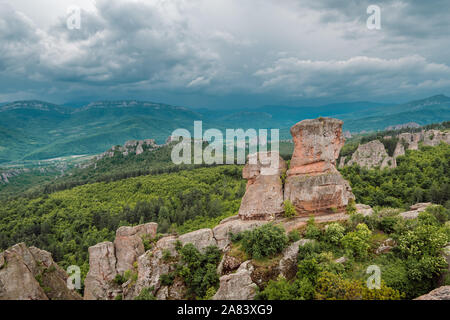 Cielo tempestoso più belle formazioni rocciose. Con il loro colore rosso contrastano splendidamente con il verde dei boschi, rocce di Belogradchik, Bulgaria. Foto Stock