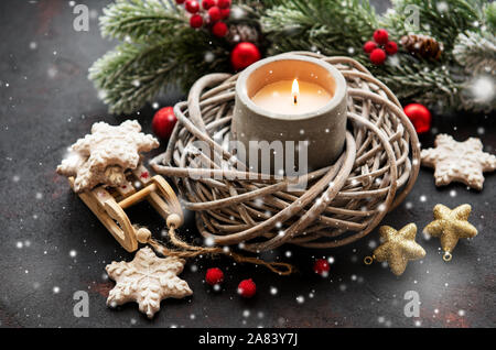 Candela che brucia con decorazione di Natale, abete, cookie baubles nero su sfondo di calcestruzzo Foto Stock