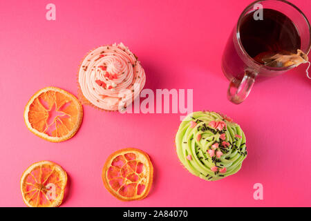 Gourmet tortine o muffin con crema di burro e decorate con cuori, su sfondo rosa. Vista dall'alto. Close-up. Foto Stock