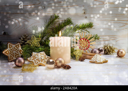 Candela che brucia con decorazione di Natale, Abete rami, baubles, stelle di paglia e gingerbread su legno rustico, snowy boheh luci, spazio di copia selezionato, Foto Stock