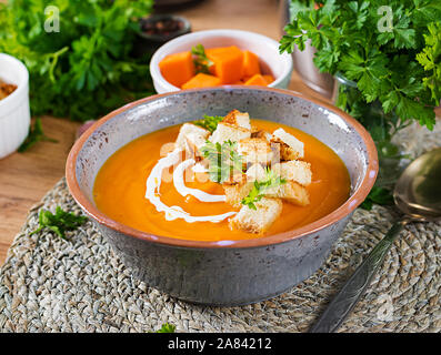 Zuppa di zucca in una terrina servita con prezzemolo e crostini. Zuppa vegan. La Giornata del ringraziamento di cibo. Pasto di Halloween. Foto Stock