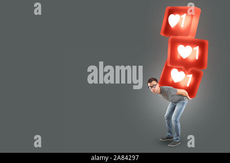 Uomo che porta una pila di grandi social media come simboli Foto Stock