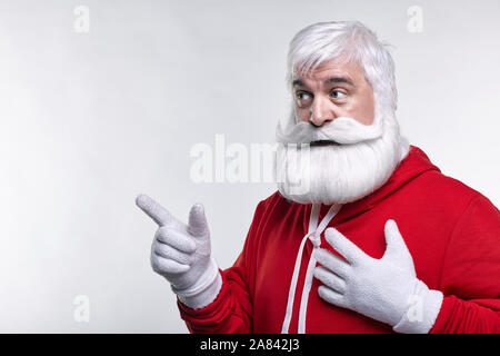 Ritratto di una Santa Claus in sportsware. Bianco-dai capelli uomo anziano con barba e baffi guardando lontano. Foto Stock