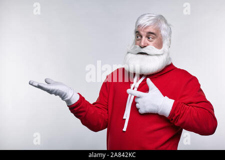 Ritratto di una Santa Claus in sportsware. Bianco-dai capelli uomo anziano con barba e baffi guardando lontano. Foto Stock