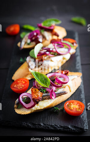 - Tapas bar spagnolo del cibo. Bruschetta con fette di pomodori essiccati,formaggio mozzarella e acciughe su sfondo scuro. Foto Stock