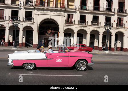 Una classica auto americana che trasporta un paio di turisti in un tour panoramico dell'Avana a Cuba. Molti degli accattivanti cabriolet classici americani c Foto Stock