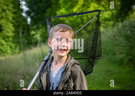 Un ragazzo che tiene una rete di pesca sopra la spalla. Foto Stock