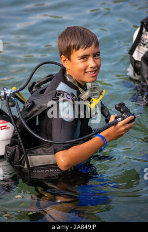 Un giovane ragazzo che indossa la piena scuba diving outfit nell'acqua. Foto Stock