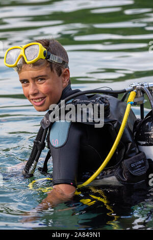 Un giovane ragazzo che indossa la piena scuba diving outfit nell'acqua. Foto Stock