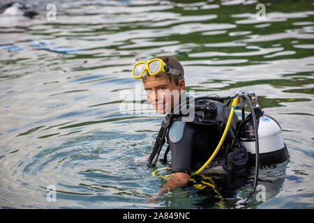 Un giovane ragazzo che indossa la piena scuba diving outfit nell'acqua. Foto Stock