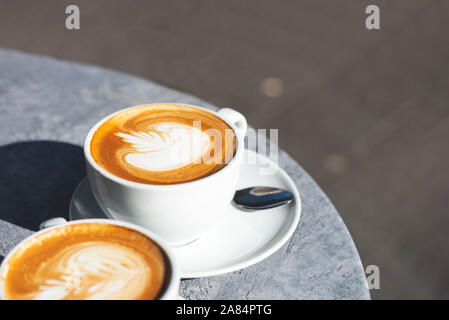 Due tazze di piatto bianco caffè nella caffetteria, bella giornata di sole, ombre sul tavolo Foto Stock