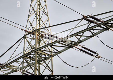 Dettaglio di alta tensione e linee elettriche ad alta tensione pilone contro il cielo grigio. Visto in Franconia / Baviera in Germania nel mese di novembre. Foto Stock