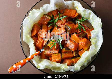 Vista superiore della zucca al forno con rosmarino su sfondo scuro. Foto Stock