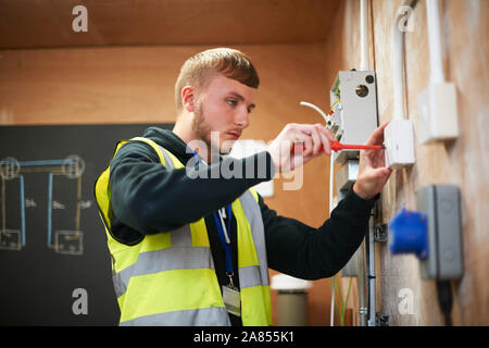 Elettricista maschio studente pratica in officina Foto Stock